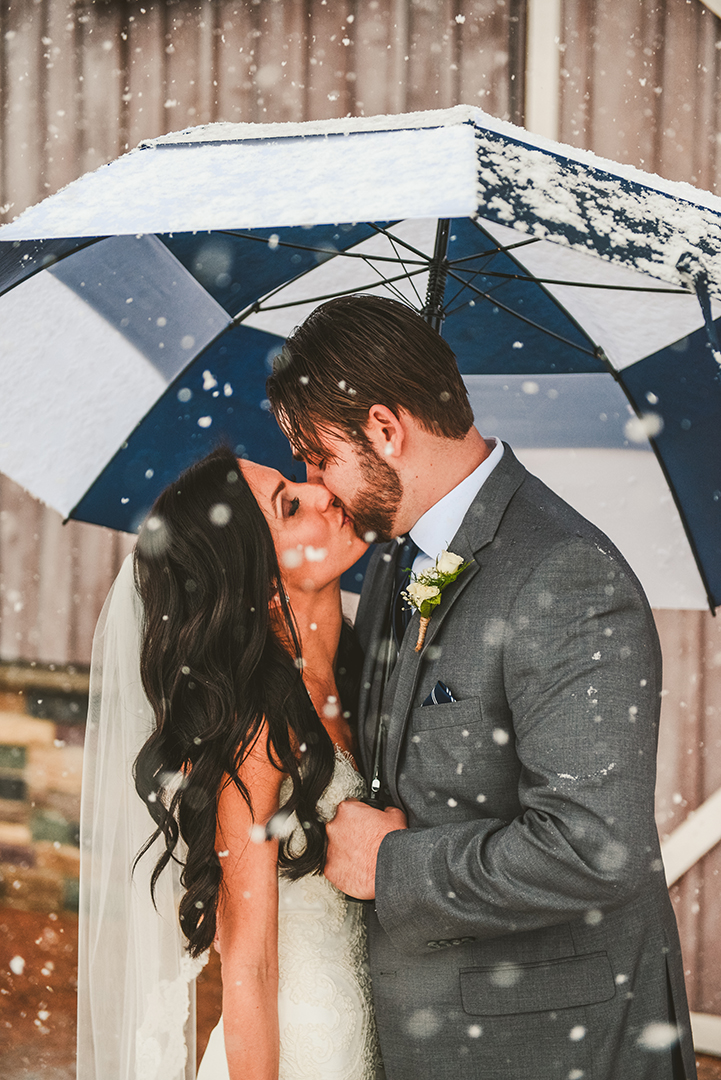 husband and wife kissing in the snow at their County Line Orchard Wedding