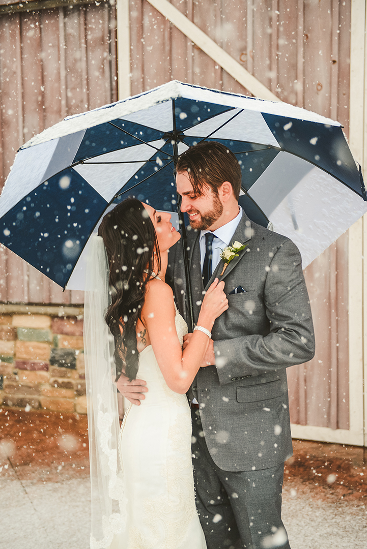a bride grabs onto her husbands jacket at a Indiana apple orchard in the snow