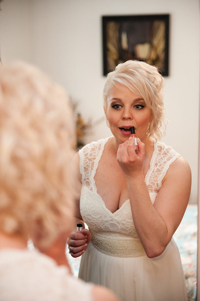 a bride putting her lipstick on in front of the mirror at a Naperville wedding