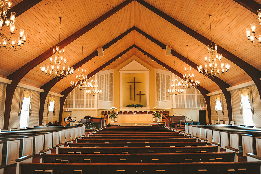 a church with beautiful wood ceilings and lit chandeliers 