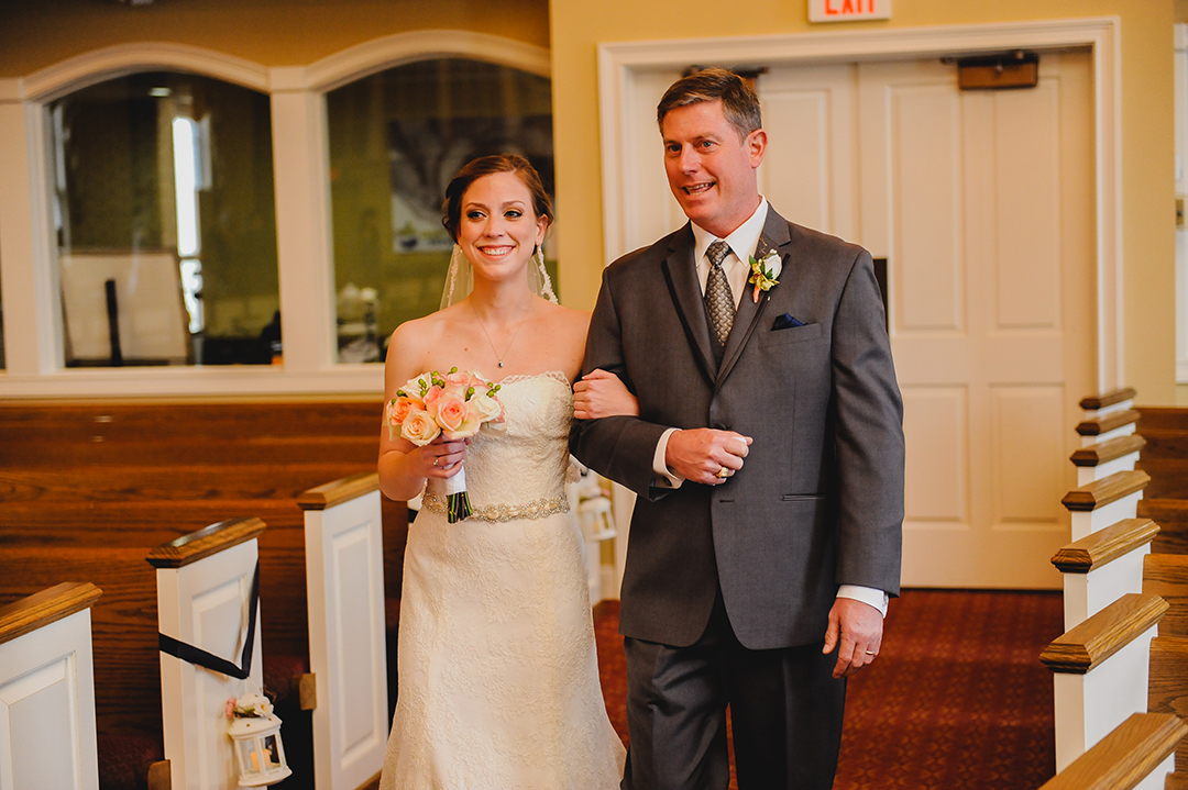 father and daughter walking down church aisle towards groom