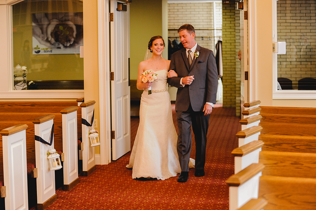 a bride walking with her dad while laughing at church