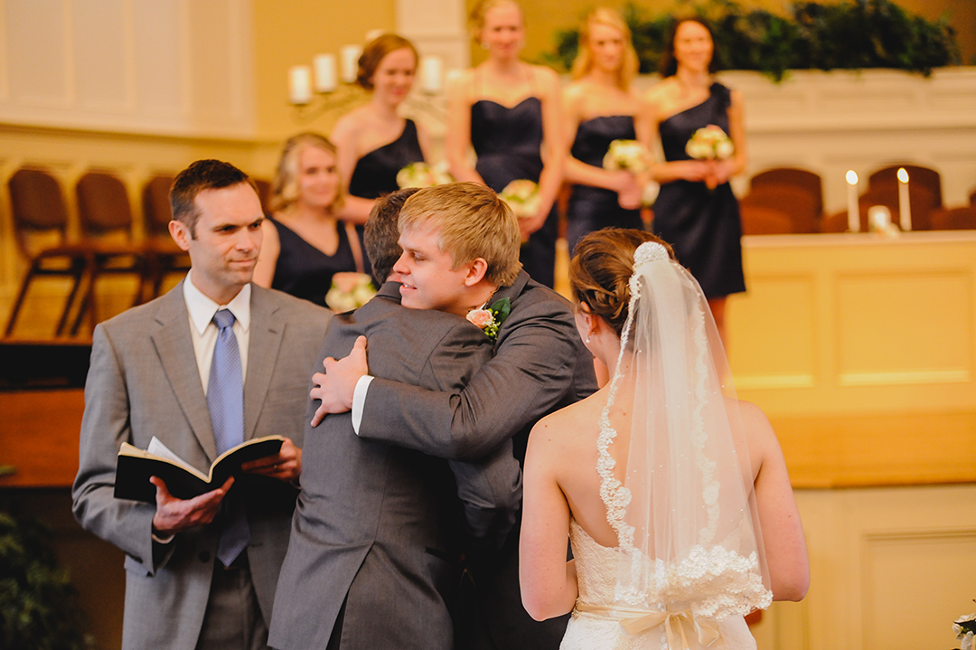 father in-law hugging groom at wedding ceremony 