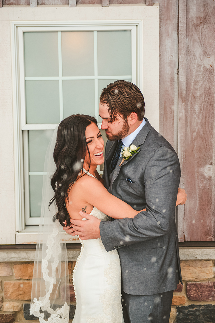 a newly married husband and wife laughing on their wedding day in the snow