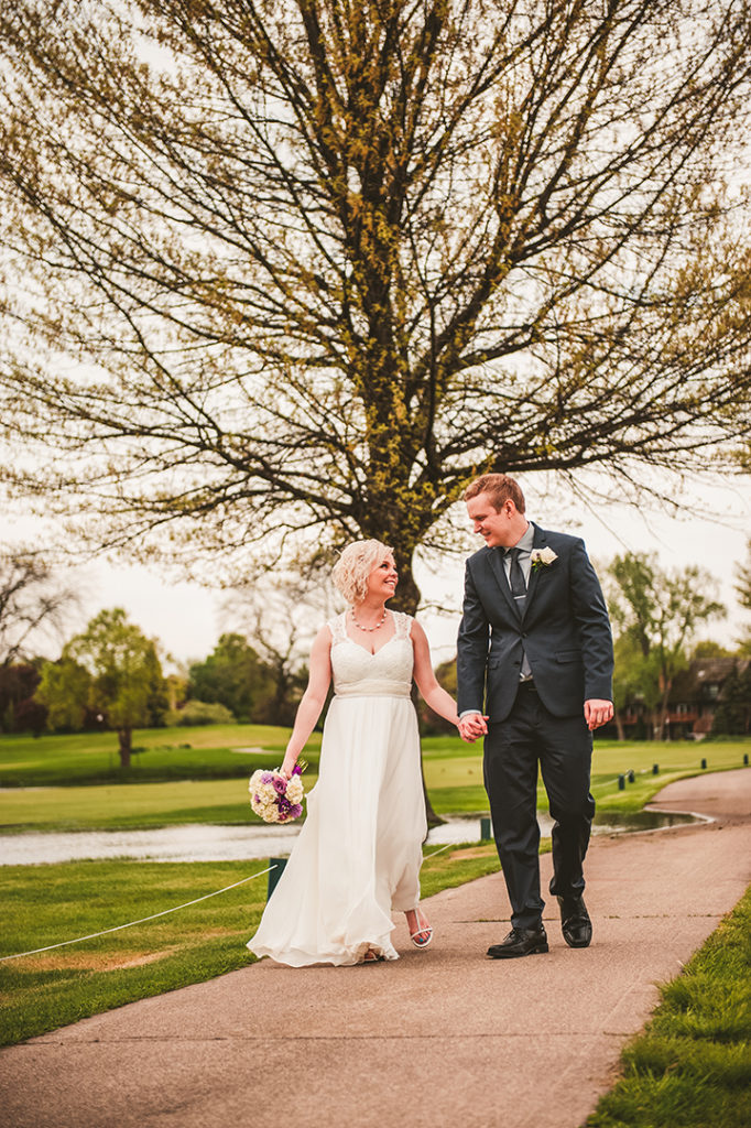 a bride and groom walking down a path while laughing