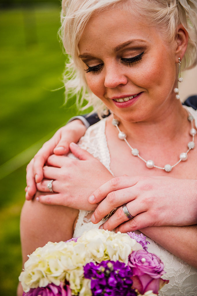 a bride looking down at grooms hands on her shoulder