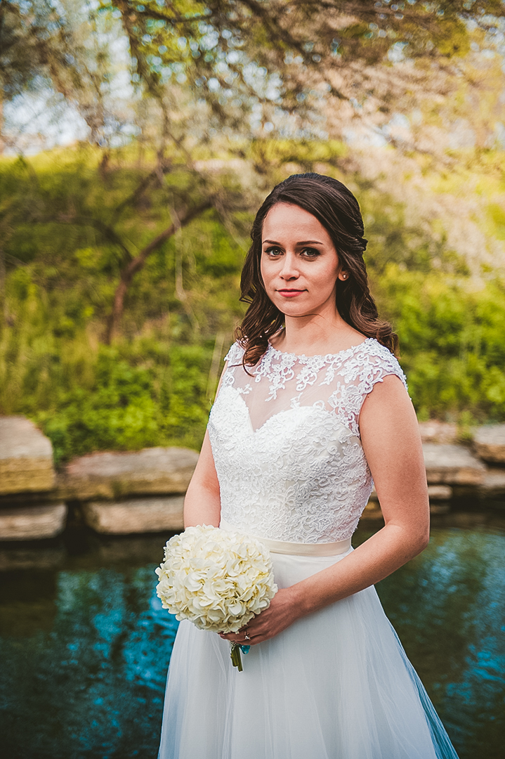 bride holding flowers with her white dress at pond
