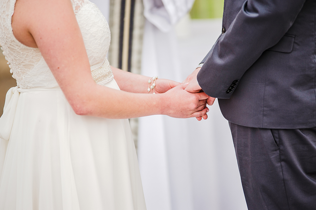 a closeup of bride and grooms hands at wedding ceremony