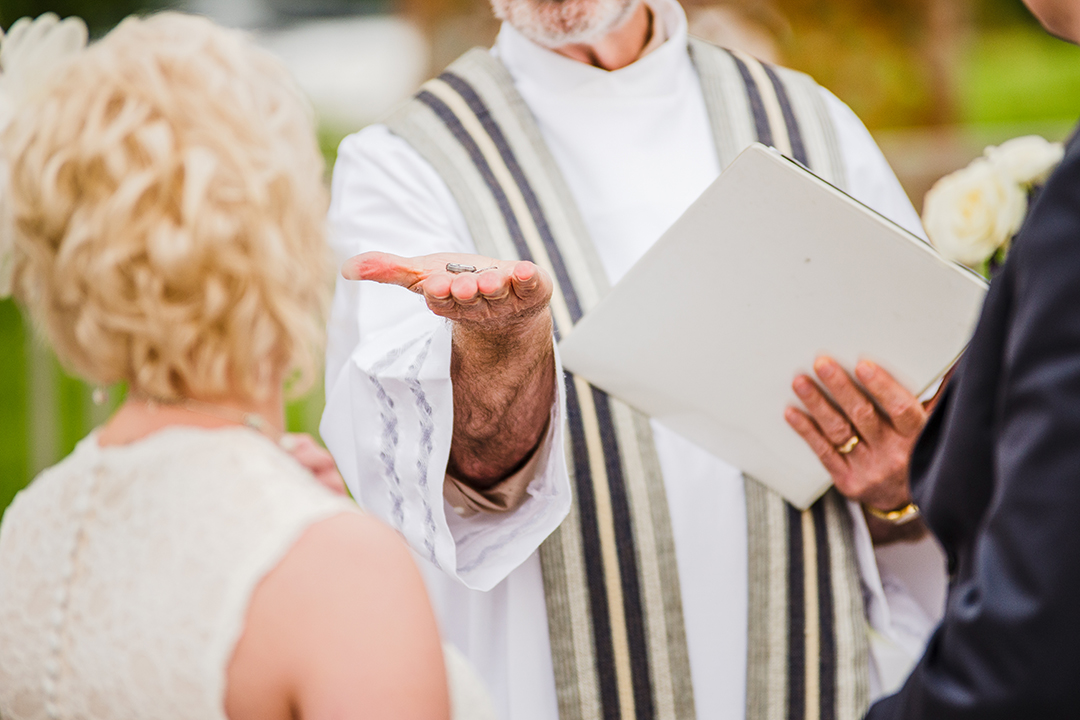 closeup up of priest holding wedding rings at ceremony