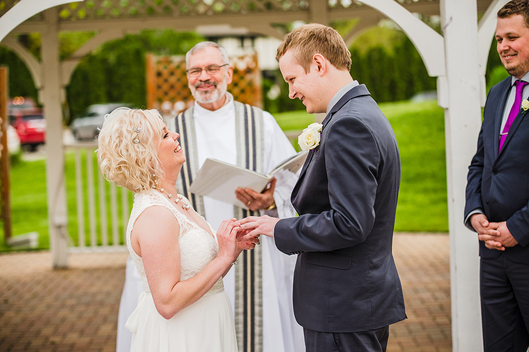 bride putting husbands ring on at their wedding ceremony