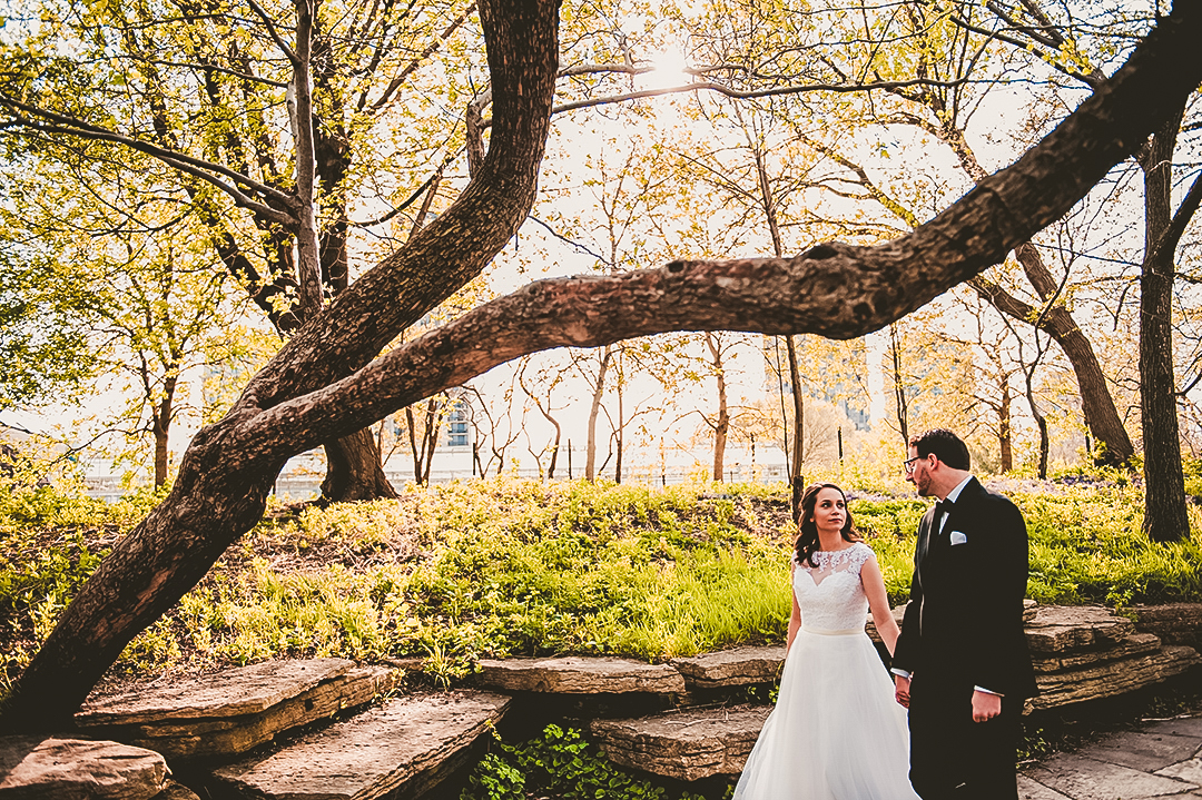 bride looking at her husband while walking under a tree