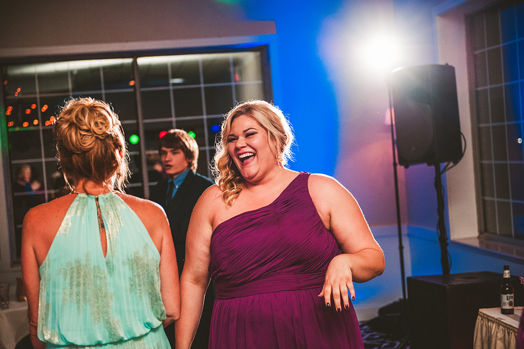 a bridesmaid laughing at a busy wedding reception