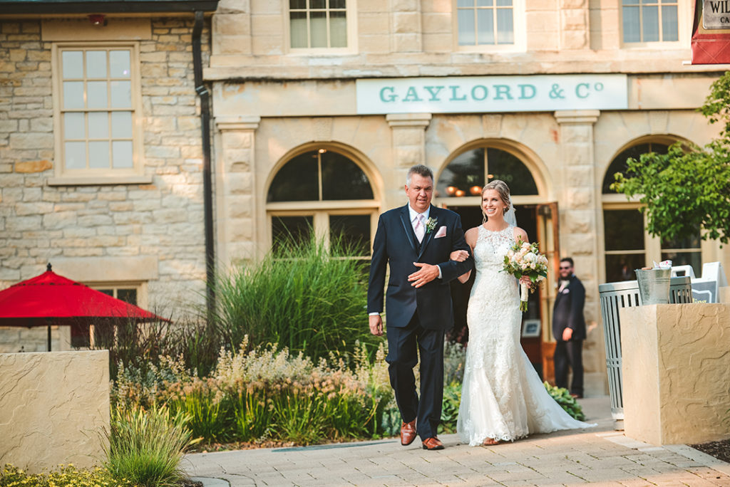 a bride and her father walk to a wedding ceremony from the historic gaylord building