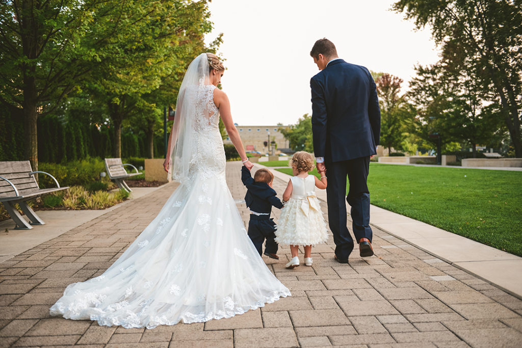 A mom and dad holding their kids hands at a wedding in Naperville Illinois.