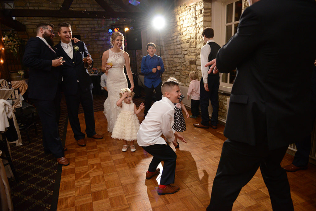 A little boy dancing at a Naperville wedding as the bride and groom look on.