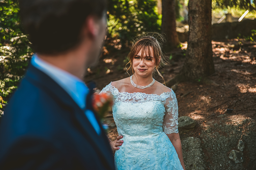 bride looking at her husband as he walks by in the woods at a Brookfield Zoo Wedding