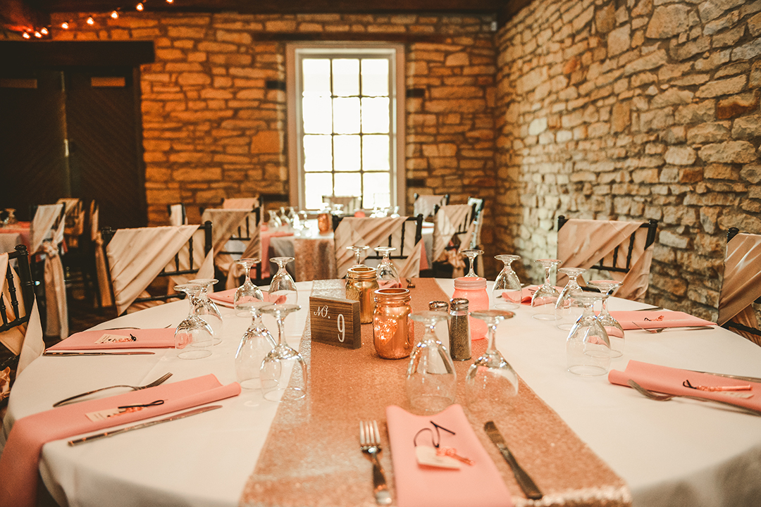 Table at wedding reception with pink napkins and white table cloth and a brick wall
