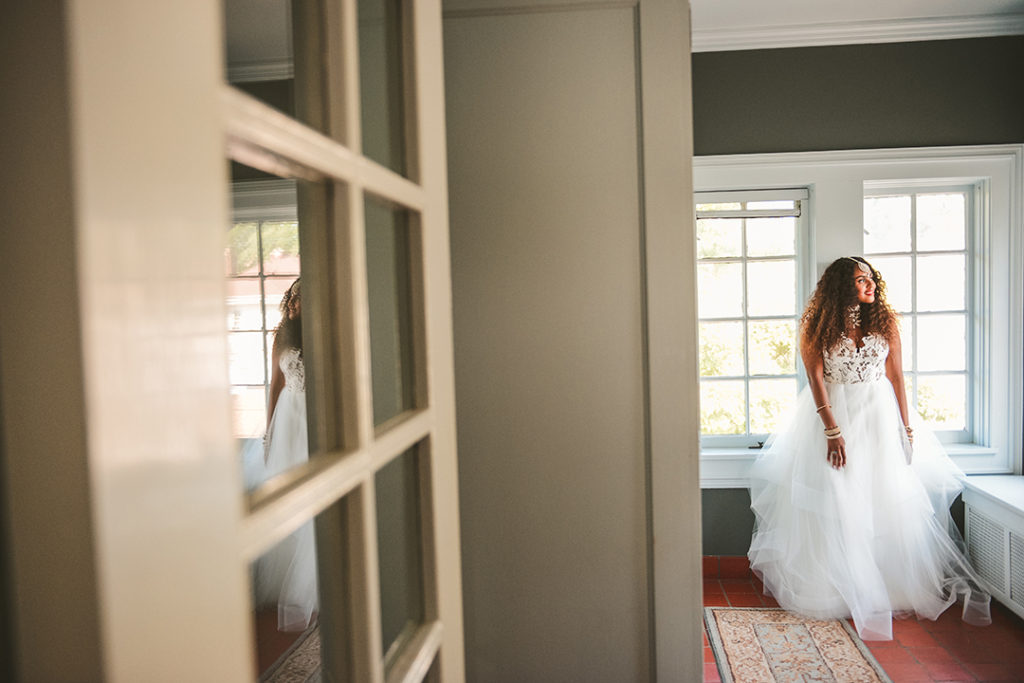 a bride looking out the window with a reflection in the window at a Chaney Mansion Wedding