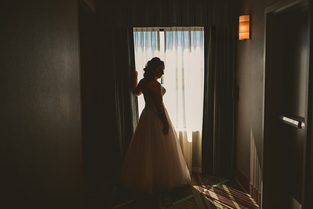 a bride stands in the hall of her hotel before her wedding