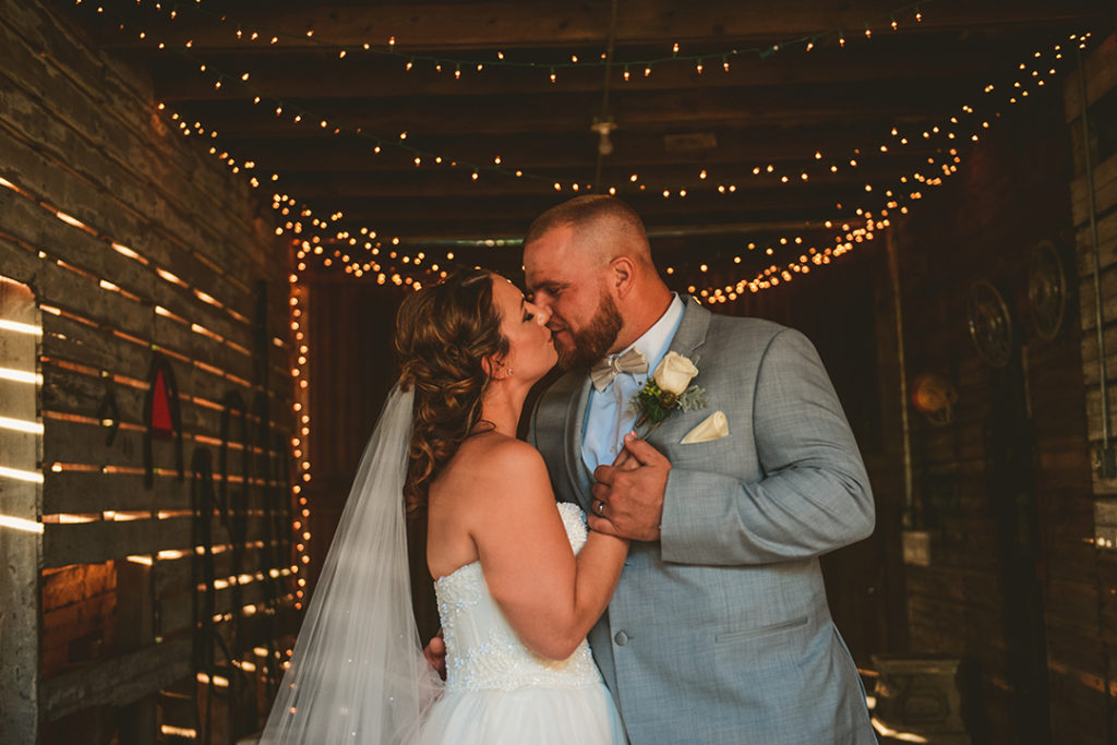 a husband and wife kissing in a rustic barn at their Northfork Farm Wedding