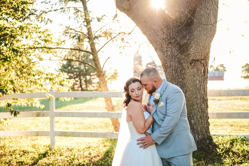 a husband and wife in a field with the setting sun in the background at their Northfork Farm Wedding