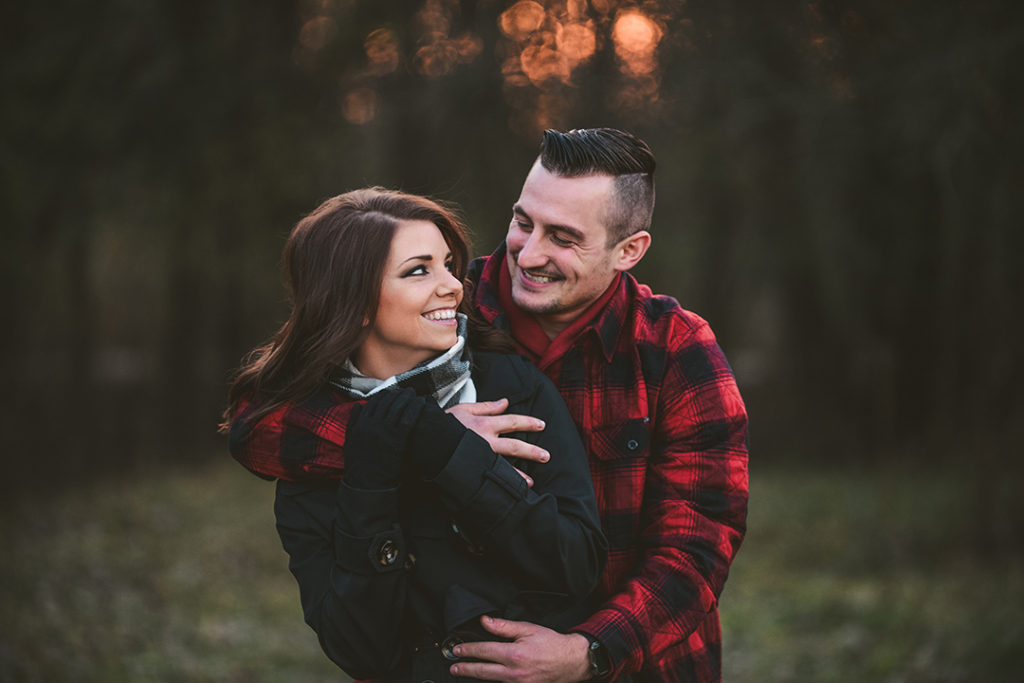 husband and wife hugging each other in the woods during a holiday photography session