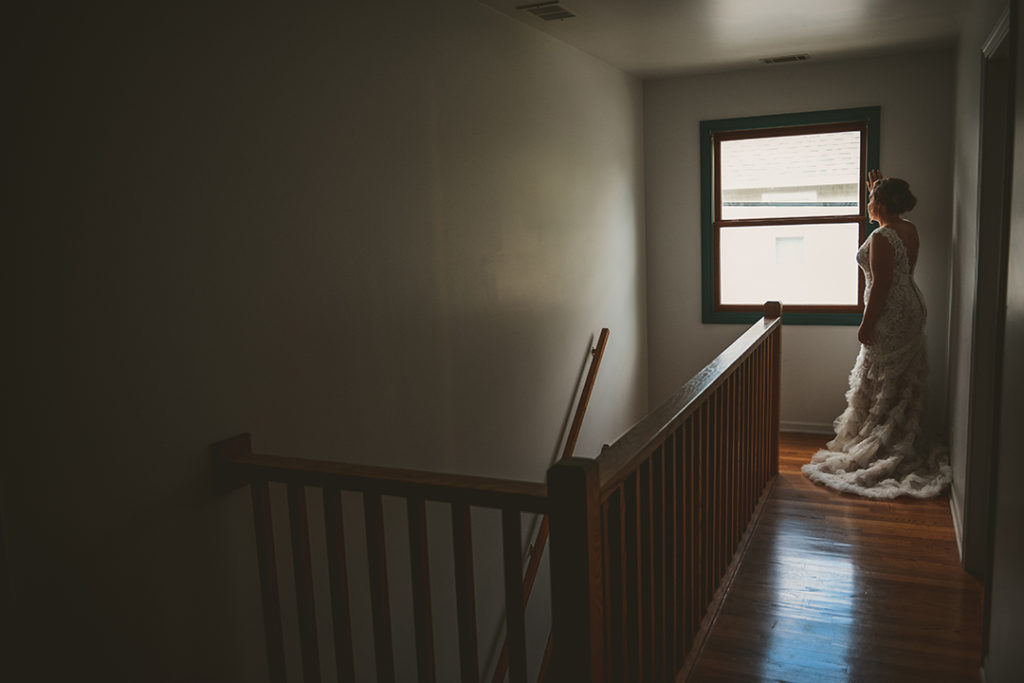 the bride looking out a window at the end of a long hallway