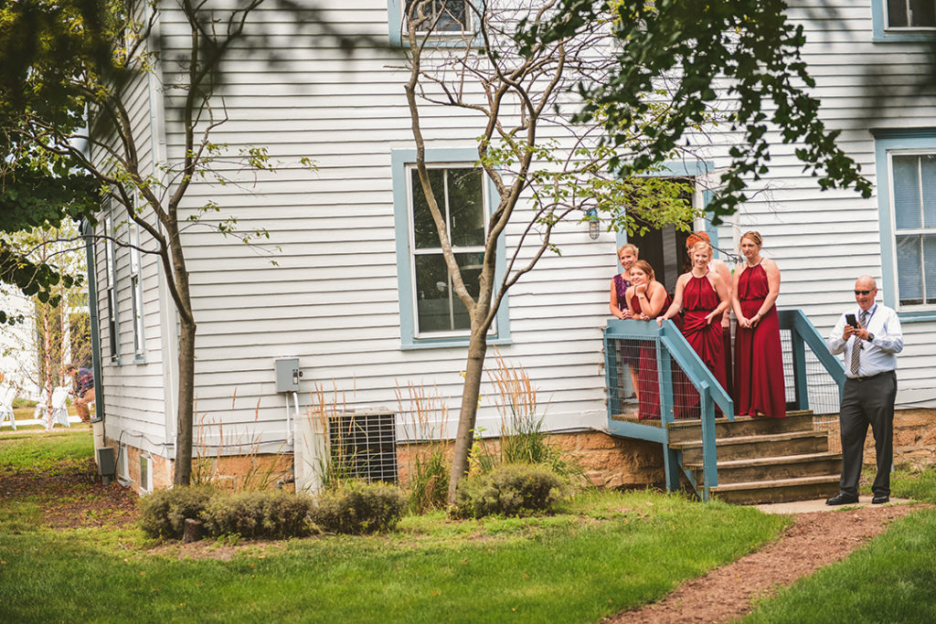 a group of bridesmaids watching as the bride and groom have their first look