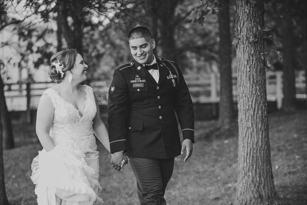 newlyweds holding hands as they walk down a wooded path in black and white