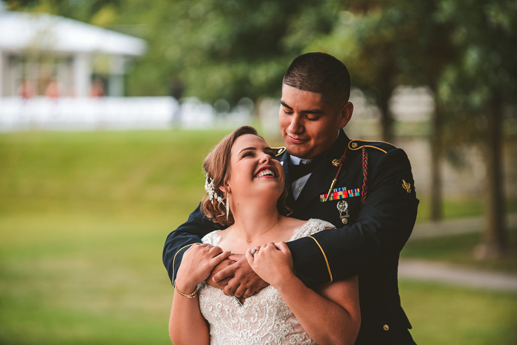 a bride looking up at her groom as he holds her in a park at Olympia Fields