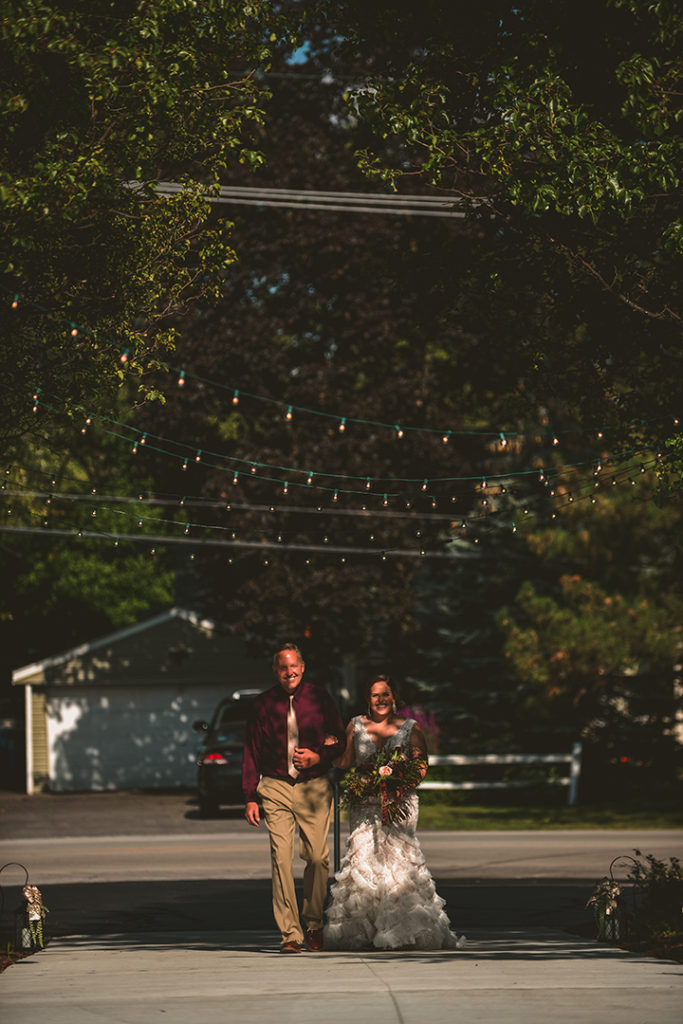 the brides father walking his daughter down the aisle in a outdoor wedding at Olympia Fields