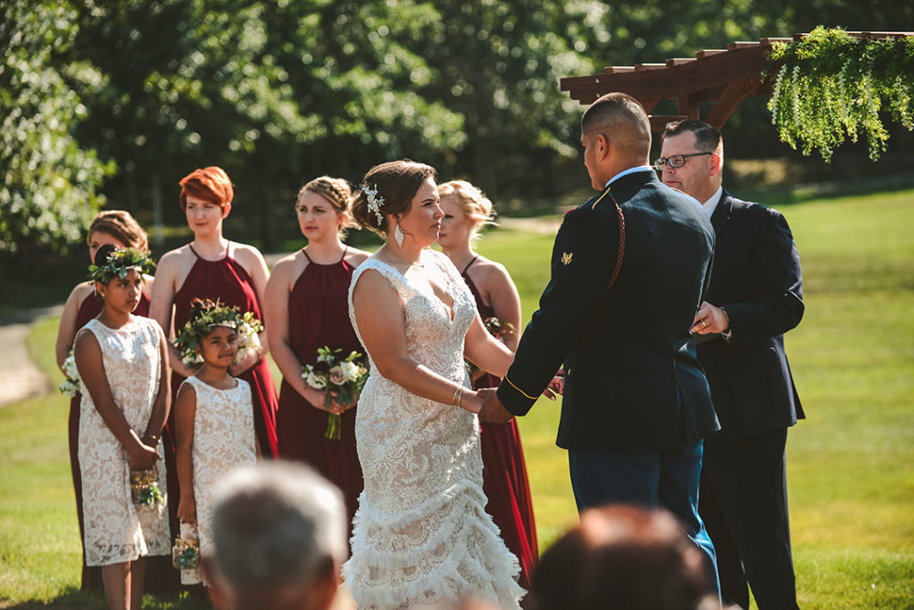 looking over a guests shoulder of the bride and groom holding hands at the alter at a wedding ceremony