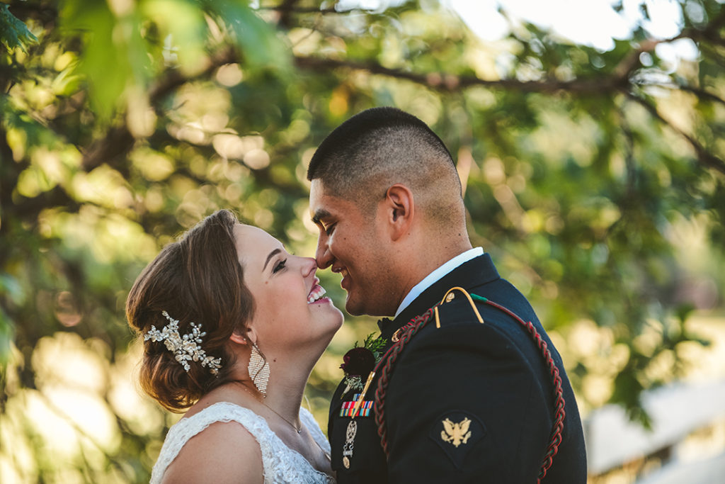 a closeup of a bride and groom kissing with green leaves in the background