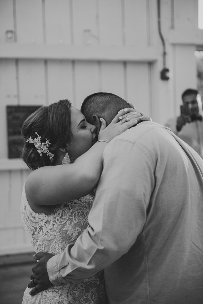 the bride whispering into her husbands ear during their first dance in black and white