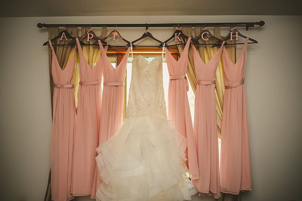 all of the bridesmaids dresses hanging with brides on custom wooden hangers