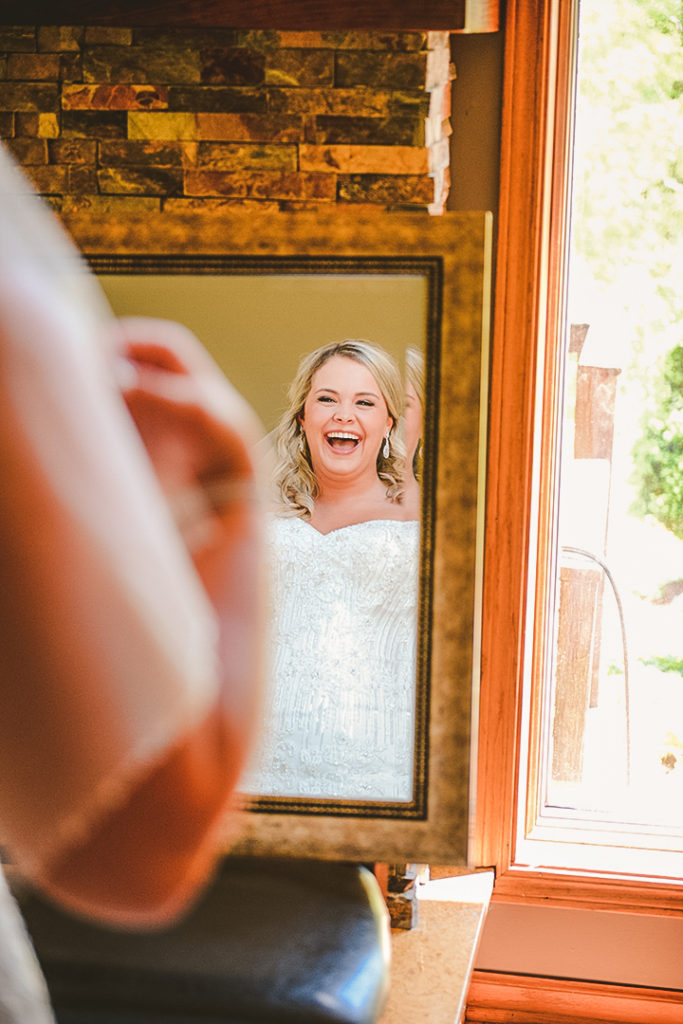 the bride laughing as she looks into a large mirror