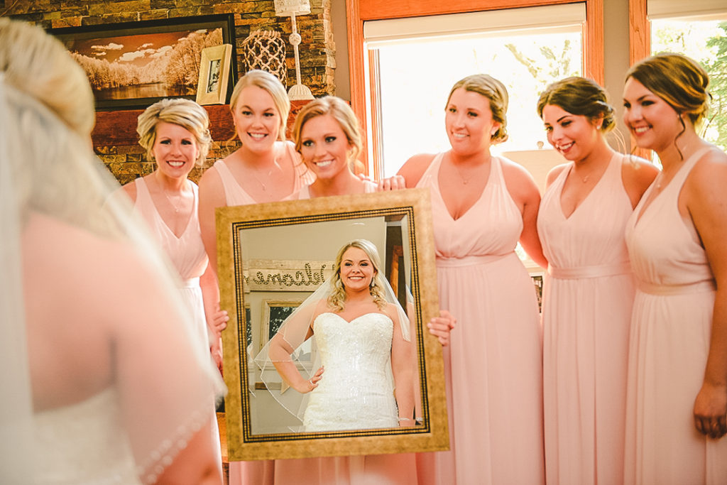 the bridesmaids holding up a mirror as the bride looks into it