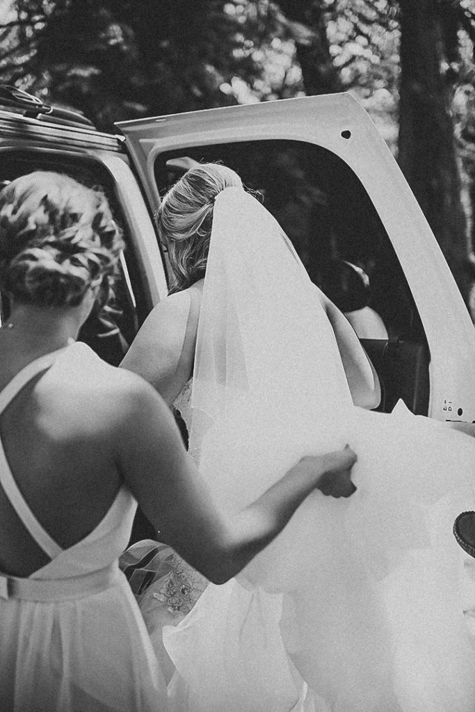 the made of honor helping the bride get into a car as they leave for the wedding ceremony