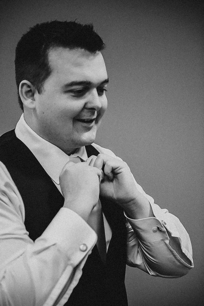 a man adjusting his tie at a church in Morris as he smiles