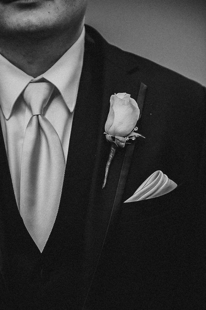 a close up of the grooms boutonniere pinned to his suit