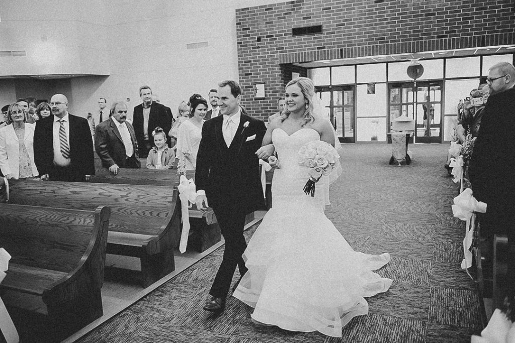 a father walking his daughter down a church aisle in front of their friends and family