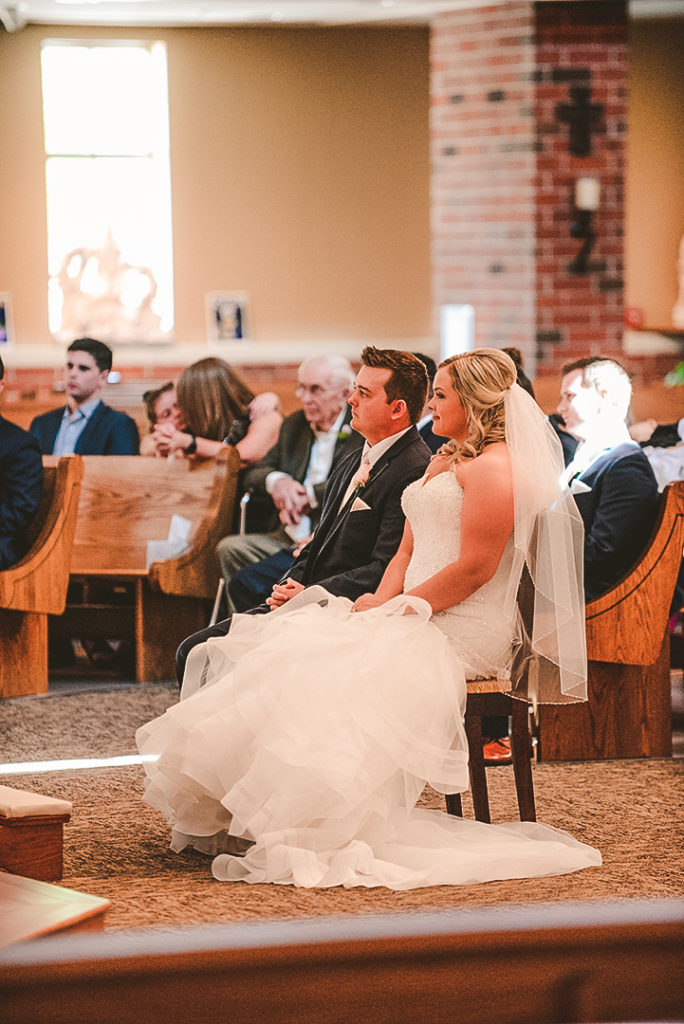 a man and woman sitting at the church alter during their wedding in Morris