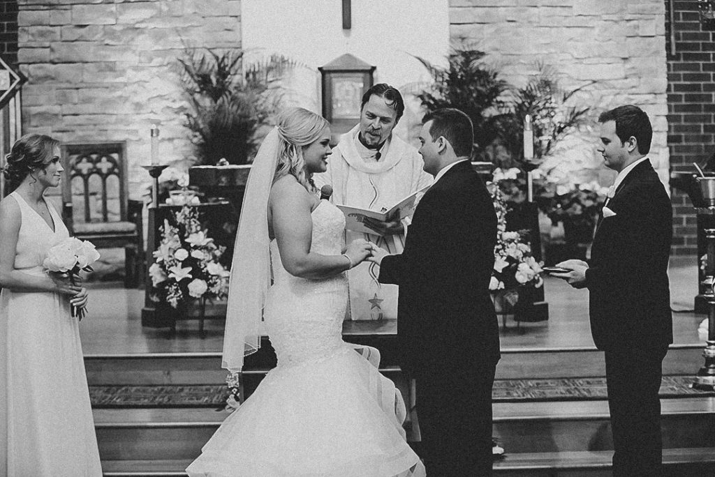 the bride laughing as she puts on the grooms ring at the church alter