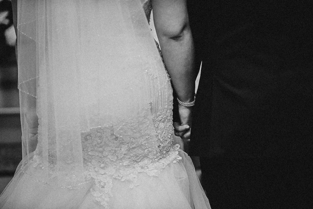 a close up of a bride and groom holding hands at the church alter on their wedding day