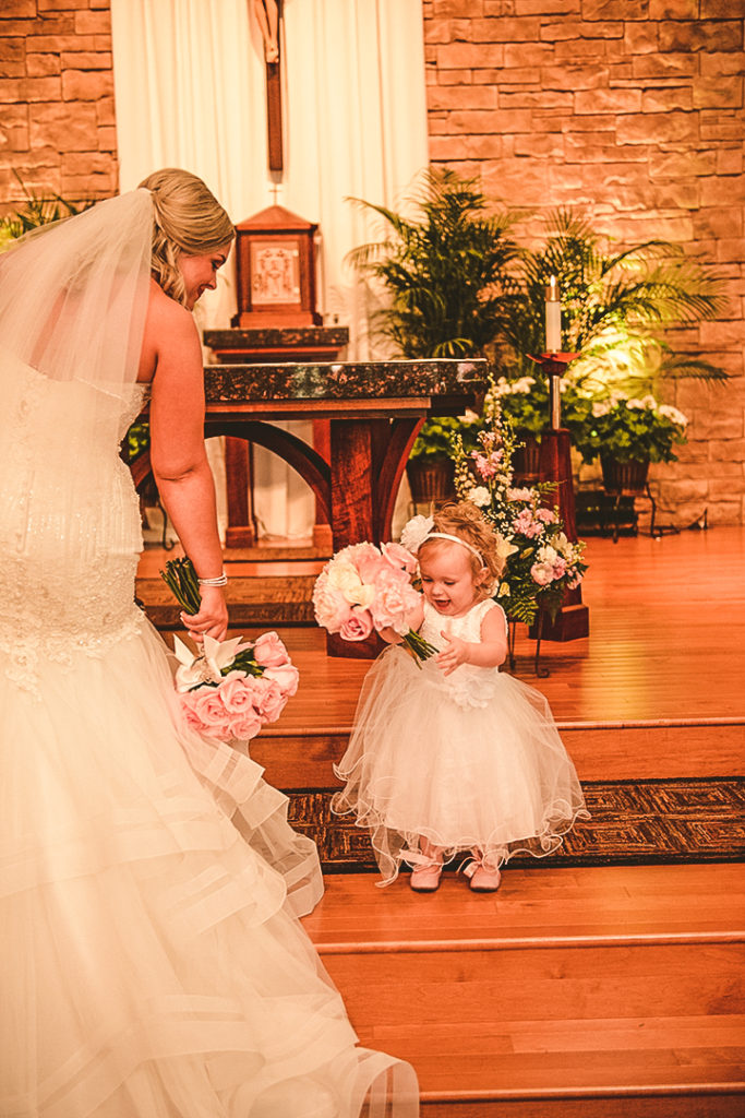 the brides daughter holding onto a bouquet while laughing at their family church