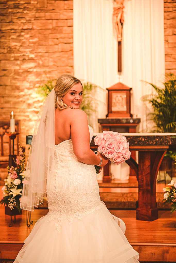 the bride showing off the back of her dress as she holds onto her pink real flower bouquet