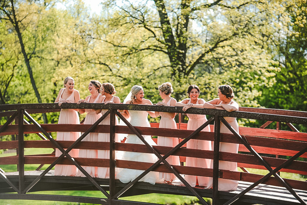 all of the bridesmaid hanging out on a bridge laughing while looking at each other