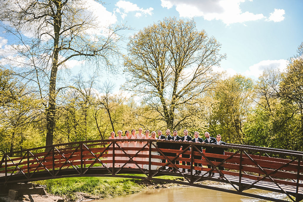 the full bridal party standing on a old bridge at the Morris Country Club