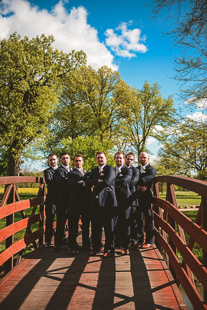 the groomsmen with their arms crossed on an old bridge in Morris