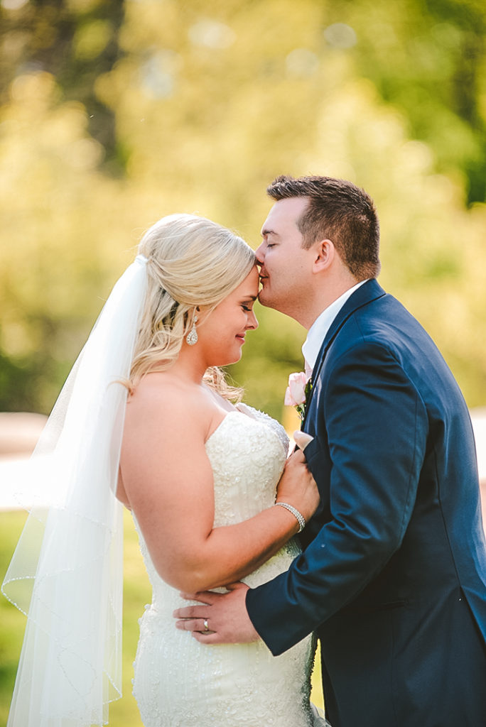 a man kissing a woman's head on their wedding day